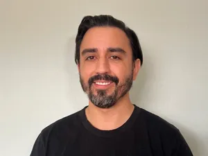 Portrait of Andrew in a black t-shirt against a blank wall
