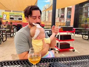 Andrew holding a baby wearing a bow outside at a brewery