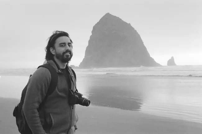 A black and white photo of Andrew Gonzales on Cannon Beach, Oregon