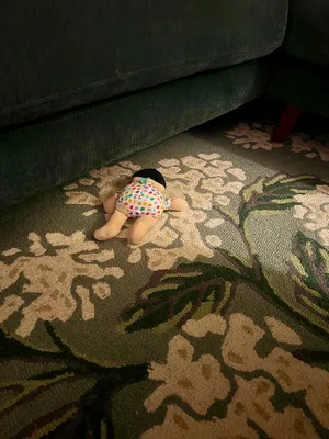 A baby doll face down on a green patterned rug