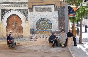 Men at the corner of a building with painting of Moroccan architecture and tilework